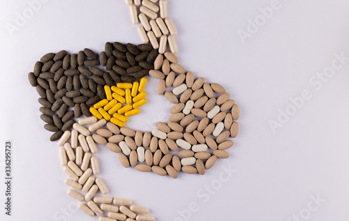 Yellow capsules as gall bladder with liver and stomach shapes made of tablets on white background. Liver medicines concept photo