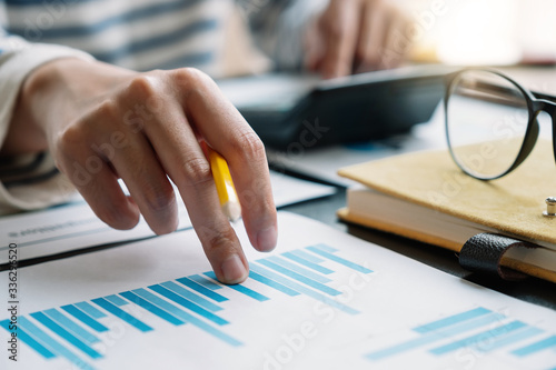 Business woman working in finance and accounting Analyze financial budget with calculator in the office