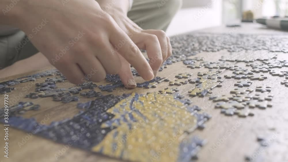 Woman solving a jigsaw puzzle in quarantine. playing board games. Close up of hands Woman solving a jigsaw puzzle in quarantine. playing board games. Close up of hands