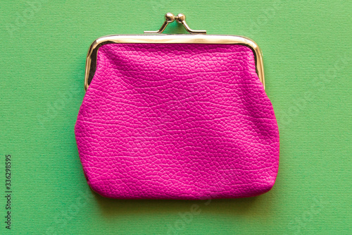Fashionable pink wallet on a light green background. Close up.