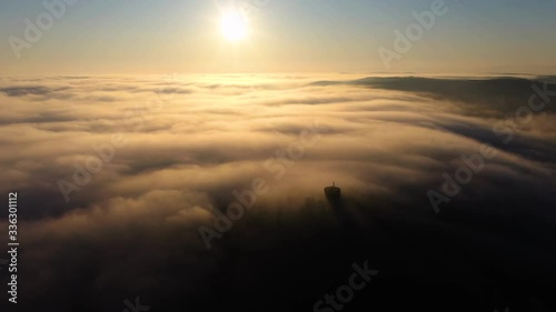 Moving drone shot over the clouds while a viewpoint is peaking out of the mist photo