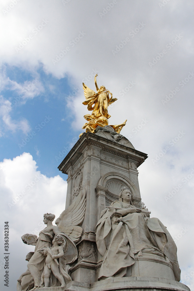 Obraz premium Gilded Winged Victory at the top of the Victoria Memorial in front of Buckingham Palace in a sunny day, London, UK