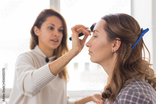 Beauty and cosmetics concept - Make-up artist doing professional make up of young woman