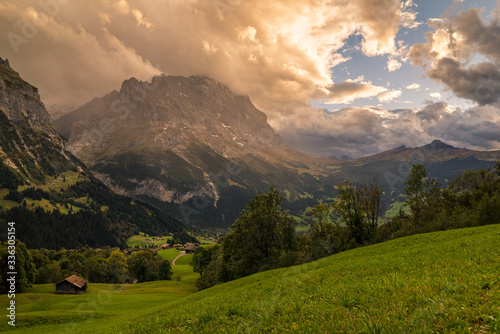 Alpine countryside landscape at sunset with the Jungfrau mountain range in the background in the alpine region of Grindelwald, Switzerland.