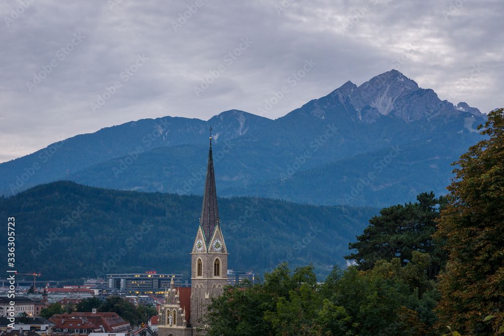  A church tower with beautiful mountains in the background in Innsbruck, Austria