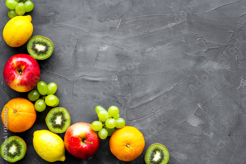 Fototapeta Naklejka Na Ścianę i Meble -  Fresh fruits background with citruses, apple, kiwi and grape on grey table top-down frame copy space
