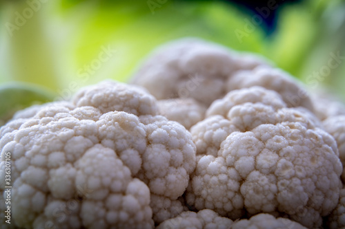 White Cauliflower close-up with green leaves on background