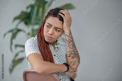 Long-haired with a tattoo on her arm looking unhappy