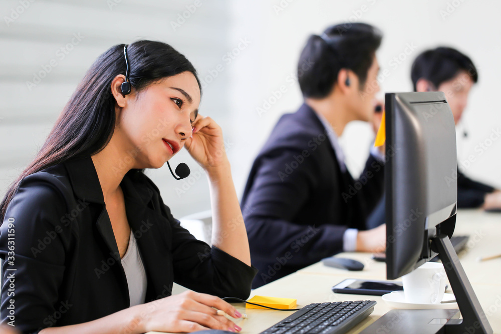 Beautiful asian woman Serious call center operator in wireless headset talking with customer,in customer support service. Beautiful asian woman Serious call center operator in wireless headset talking with customer,in customer support service.