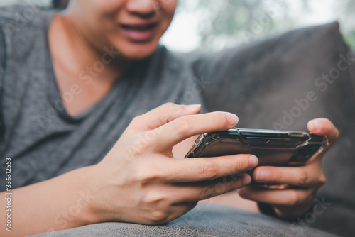 Closeup image of Asian woman holding smartphone using and looking at that with feeling happy.