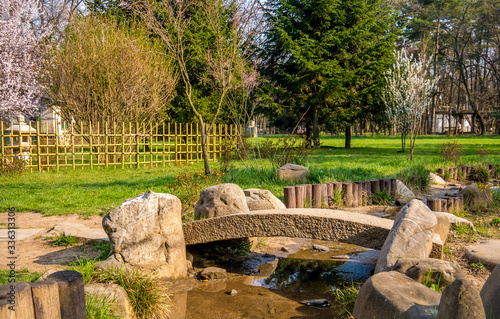 Japanese garden pond in the spring. Beautiful Japanese garden with green grass, trees and a stone bridge.