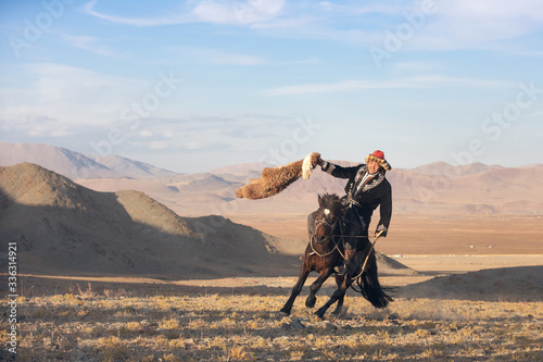 Kazakh eagle hunter after winning a traditional wrestling match. Two wrestlers on horseback start pulling on a sheep skin, the one who retrieves it, is the winner. Ulgii, Mongolia.