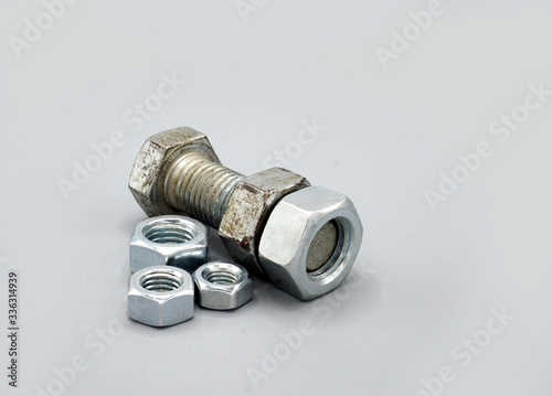 Metal screws and nuts isolated on gray background. New and shiny chrome screws and nuts. Copy space.