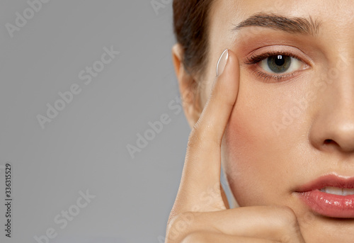 beauty, makeup and vision concept - close up of beautiful young woman face and eyes over grey background