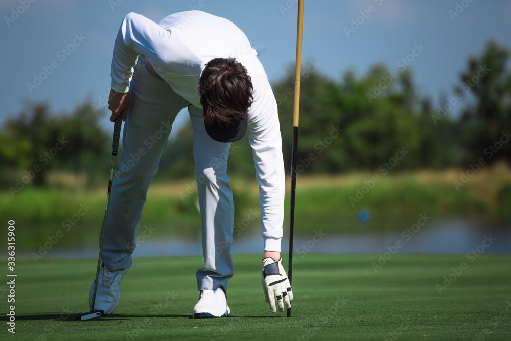 Obraz premium Professional golfers pick up golf balls in the holes, golf clubs in their hands, white and black golf gloves, hats and white golf shoes.