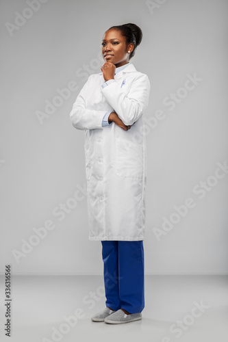 medicine, profession and healthcare concept - smiling african american female doctor or scientist in white coat over grey background photo