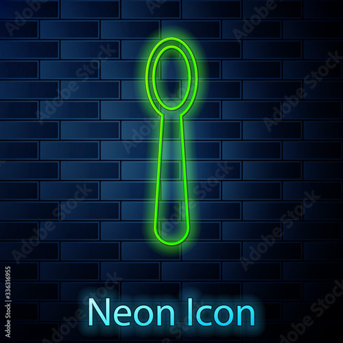 Glowing neon line Disposable plastic spoon icon isolated on brick wall background. Vector Illustration