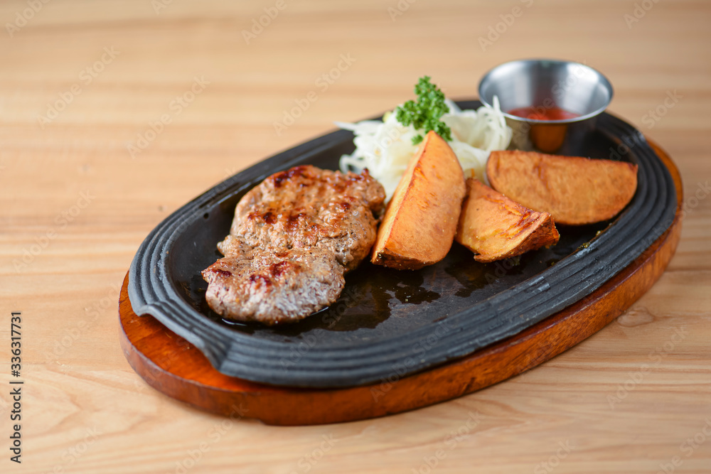 Grilled steak with vegetables and tomato sauce served on a black plate over light rustic background. Baked potato. Grilled steak with vegetables and tomato sauce served on a black plate over light rustic background. Baked potato.