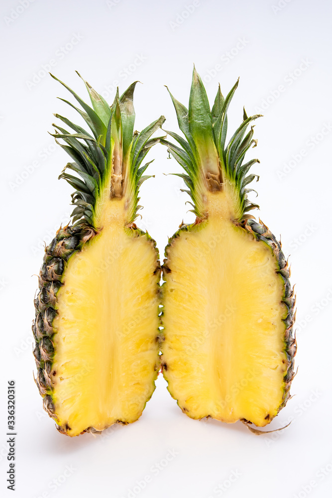 pineapple cut in half isolated in front of a white background. The yellow core of the fruit is juicy and colorfull with green leaves pineapple cut in half isolated in front of a white background. The yellow core of the fruit is juicy and colorfull with green leaves