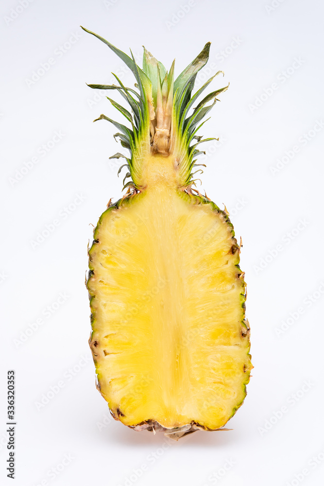 pineapple cut in half isolated in front of a white background. The yellow core of the fruit is juicy and colorfull with green leaves pineapple cut in half isolated in front of a white background. The yellow core of the fruit is juicy and colorfull with green leaves