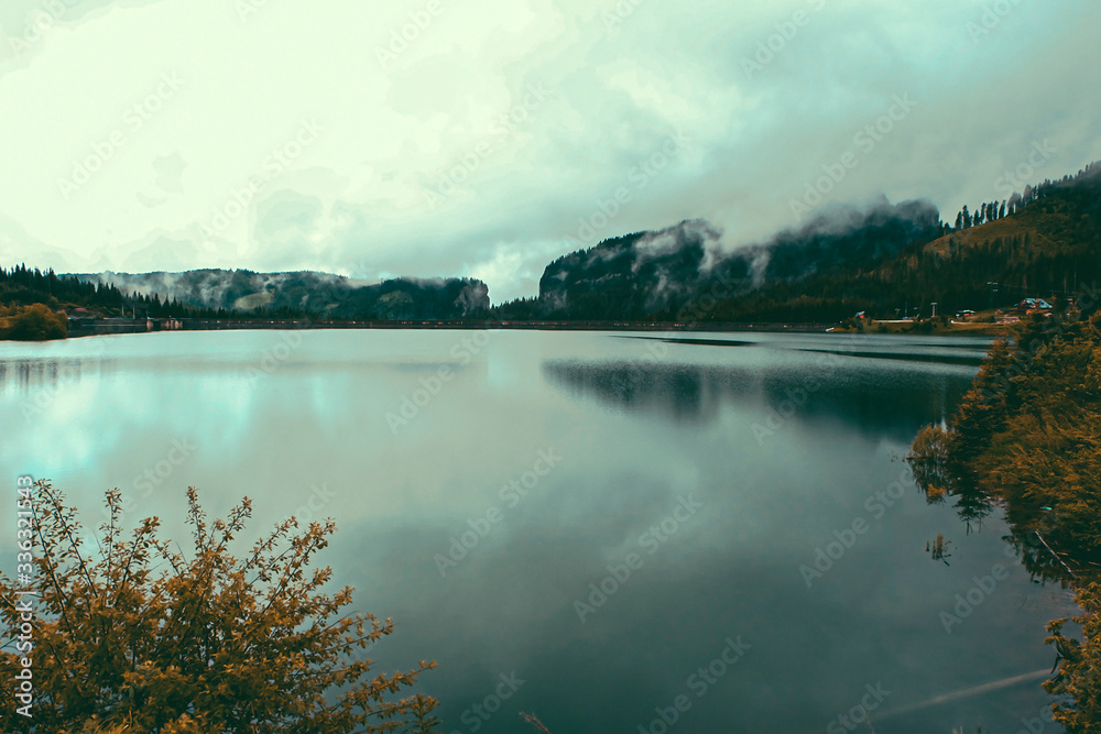 Fototapeta premium Panorama Mountain Foggy Carpathian Mountains peaks on a foggy autumn morning and lake view. Bucegi Mountains, Romania Europe