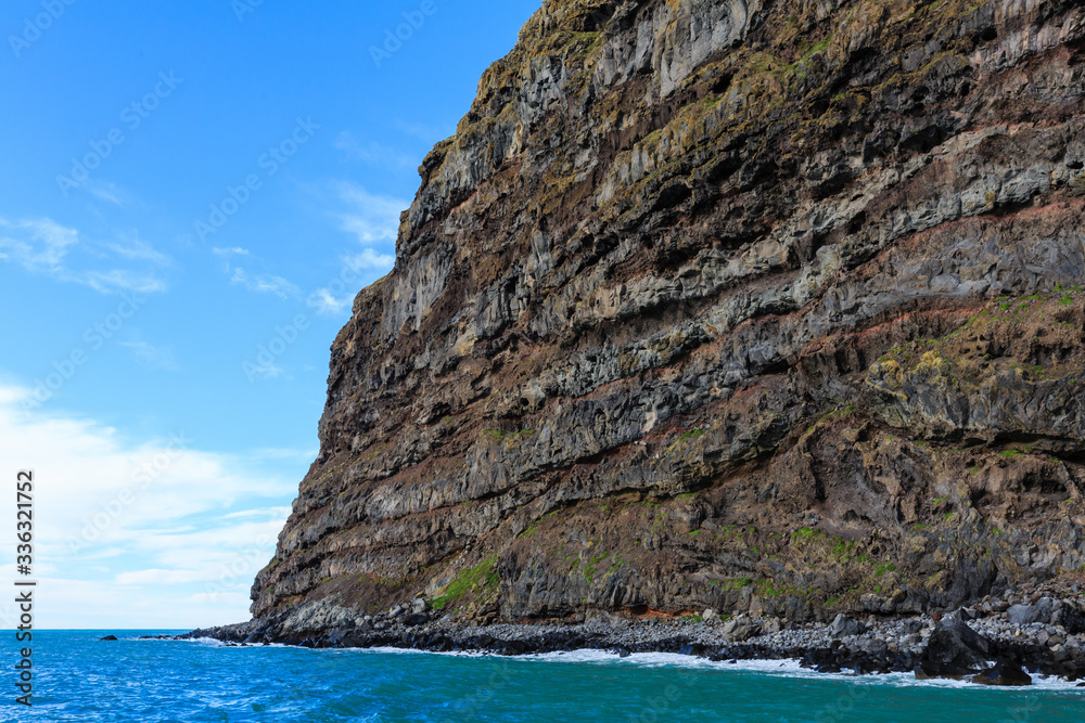 A towering sea cliff made of layers of volcanic rock at the entrance to Akaroa Harbour on Banks Peninsula, New Zealand
