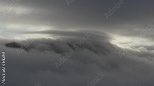 Drone shot of clouds creeping up a moutnain with multiple layers around them photo