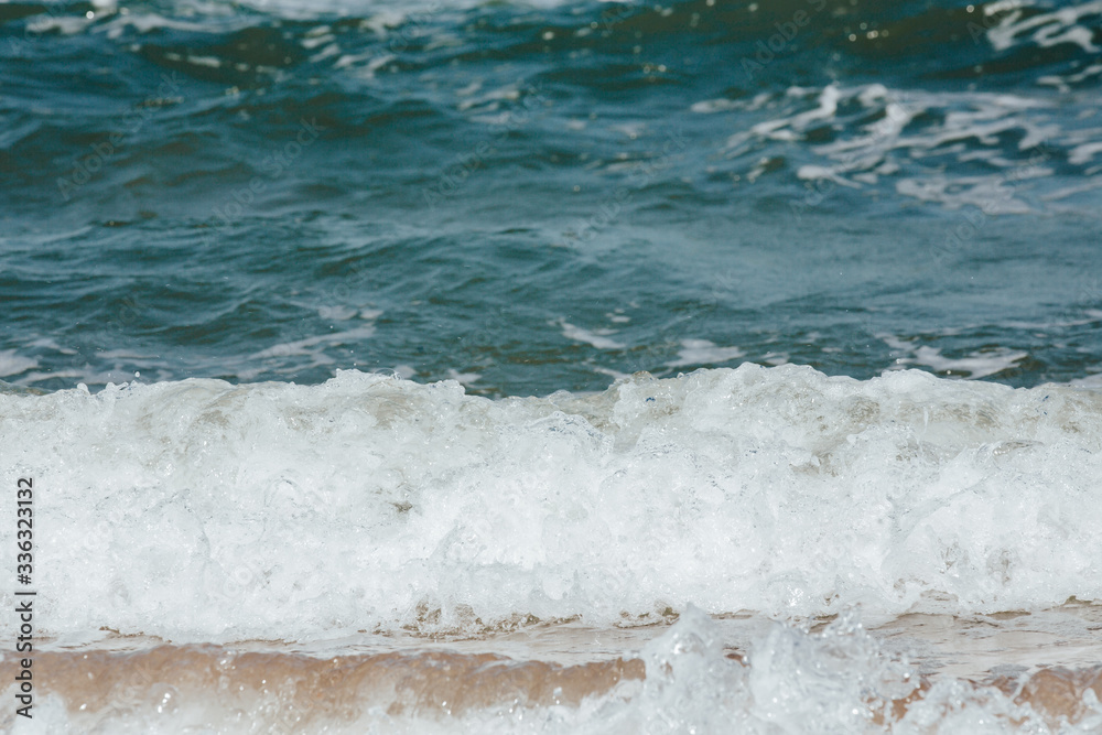 Fototapeta premium Blue sea wave with yellow sand on the shore