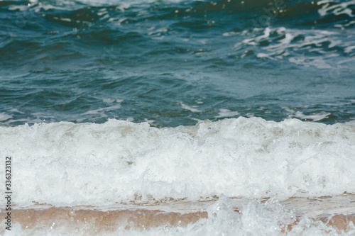 Blue sea wave with yellow sand on the shore