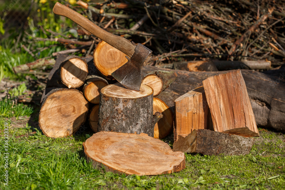Firewood with an ax in a clearing with green grass Firewood with an ax in a clearing with green grass