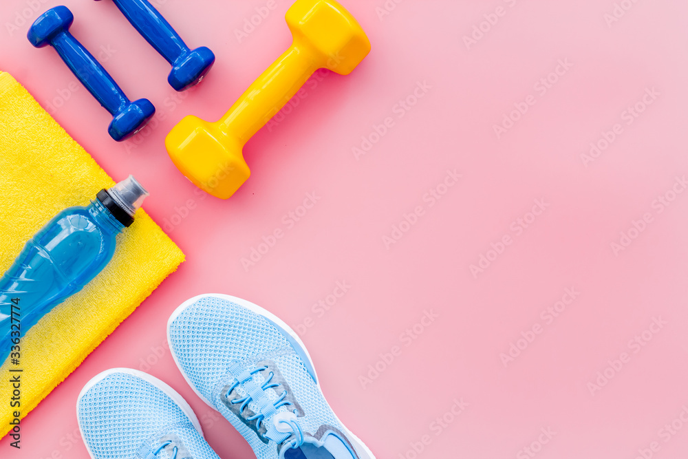 Athletics accessories. Dumbbells, towel, sneakers on pink background top-down copy space