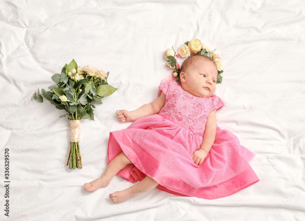 Cute little baby girl with beautiful flowers lying on bed Cute little baby girl with beautiful flowers lying on bed