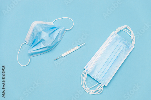 Personal protection against infection with coronavirus: face masks and thermometer on a blue background photo