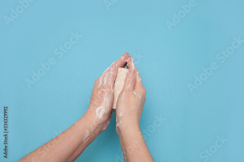 Hands using hygiene antiseptic soap on a blue background overhead top view 