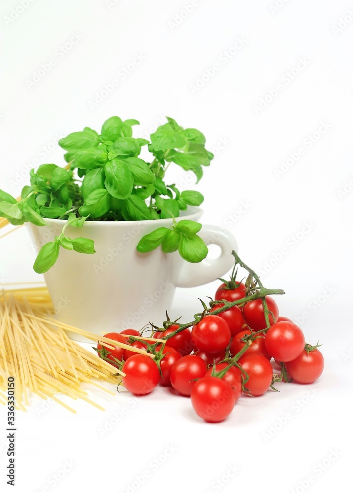 close up of spaghetti, tomatoes and a cup with basil on the white background close up of spaghetti, tomatoes and a cup with basil on the white background