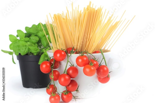 closeup of cherry tomatoes, spaghetti and basil jar on a white background 