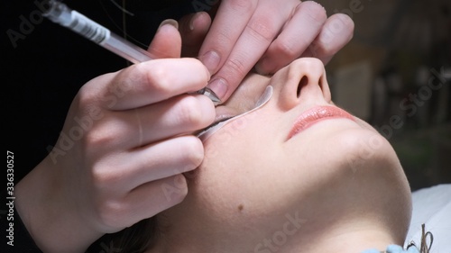 Eyelash extension procedure. Master tweezers fake long lashes beautiful female eyes © Евгения Медведева