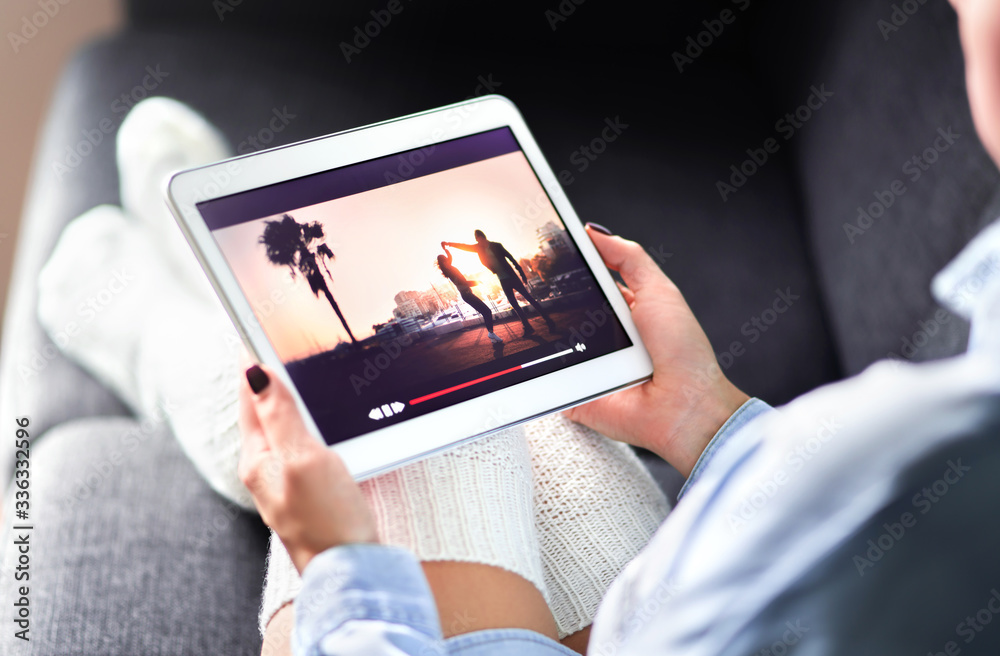 Streaming movie with VOD service. Woman watching online tv series stream. Video on demand app in tablet screen. Television program or film in smart device screen. Media network and technology.