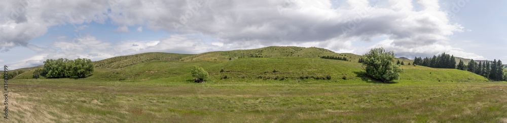 green plains in hilly valley countryside, near Lindis Valley, New Zealand
