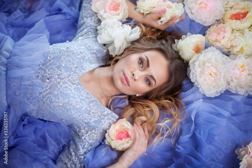 beautiful girl in a blue dress on a bed with flowers