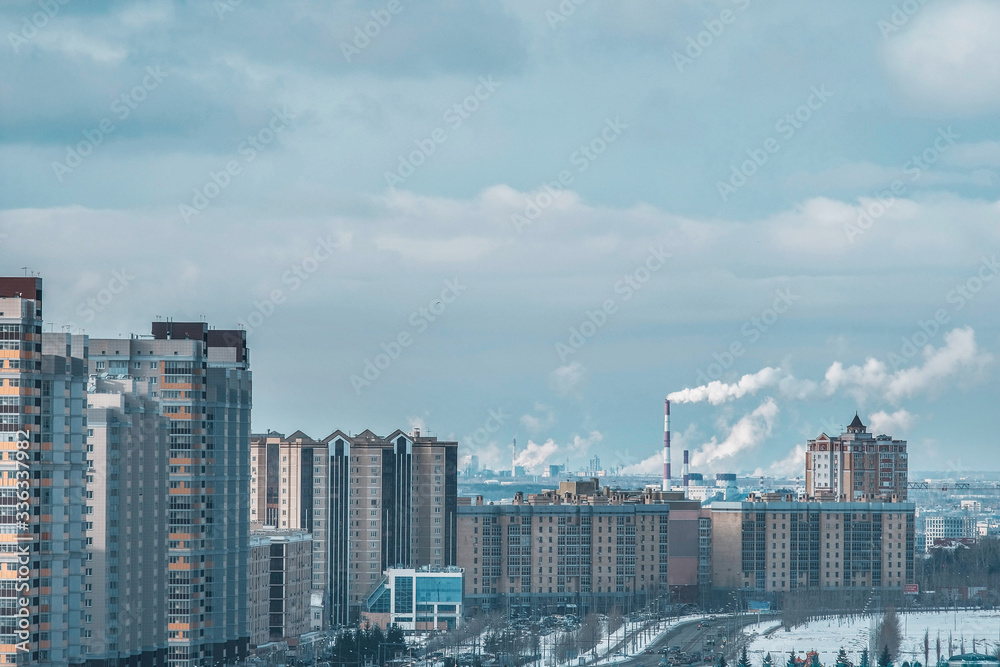 The concept of city pollution by numerous factories in Russia smoke from pipes against the background of residential tall multi-storey buildings