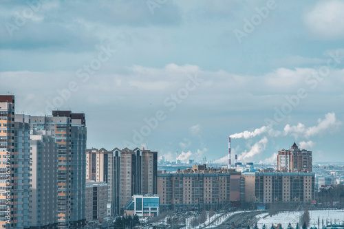 The concept of city pollution by numerous factories in Russia smoke from pipes against the background of residential tall multi-storey buildings