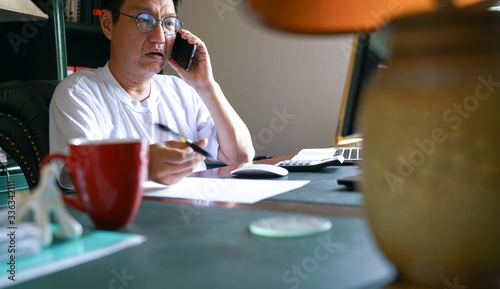 Man working from home, on his cell phone and facing his computer screen