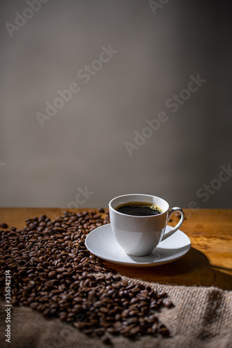 Cup of coffee and coffee beans on burlap sack. Arrangement of coffee cup and coffee beans with copy space.