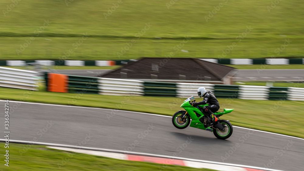 A panning image of a green racing bike passing on one wheel.