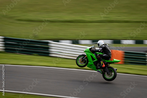 A panning image of a green racing bike passing and leaving the ground altogether.