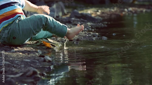 Close on toddler feet stepping into river then slipping and falling on bottom