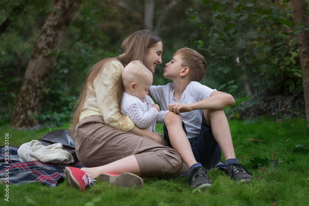 Young mother with two children resting on nature. Mother love and care. Happy family Young mother with two children resting on nature. Mother love and care. Happy family