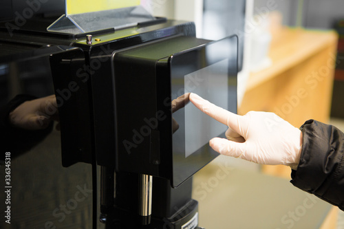 hand in a white glove touches the screen on a vending machine in a supermarket. epidemic safety