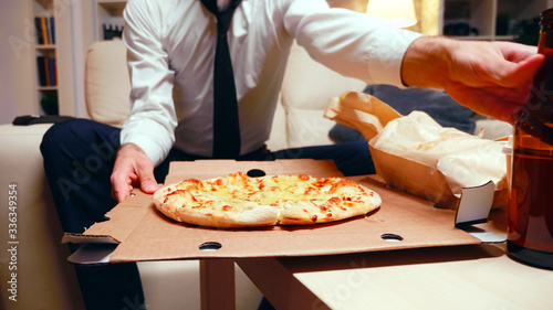 Businessman arriving home with pizza after a long day at work
